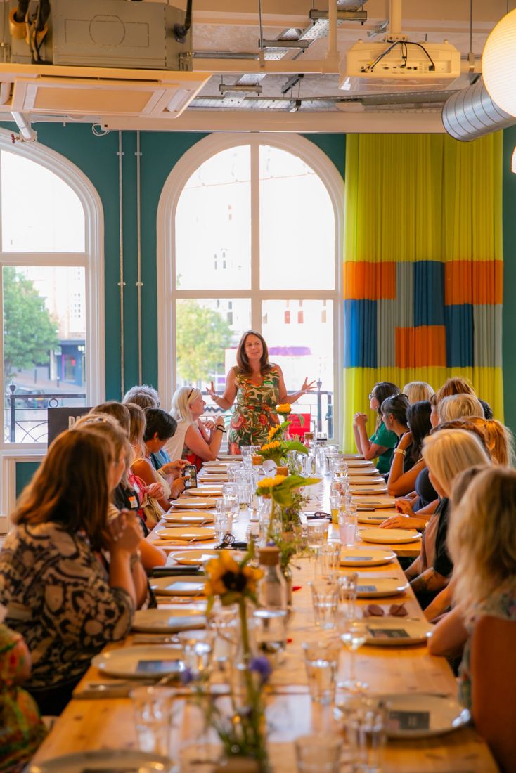 Kelly Keating facilitating a conversation with a large group around a long table
