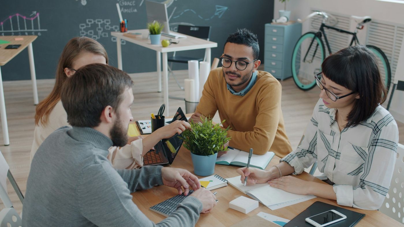 A small team in discussion around a table, making notes together